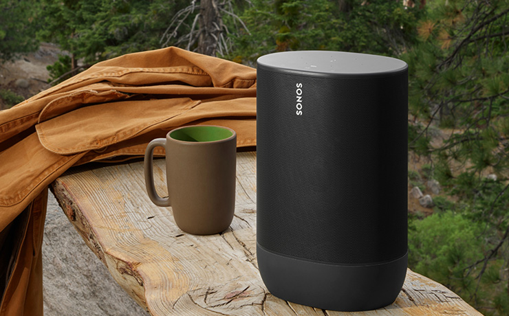 Sonos Move in black on a wooden bench with a mug beside it and an amber coloured jacket laying on the bench