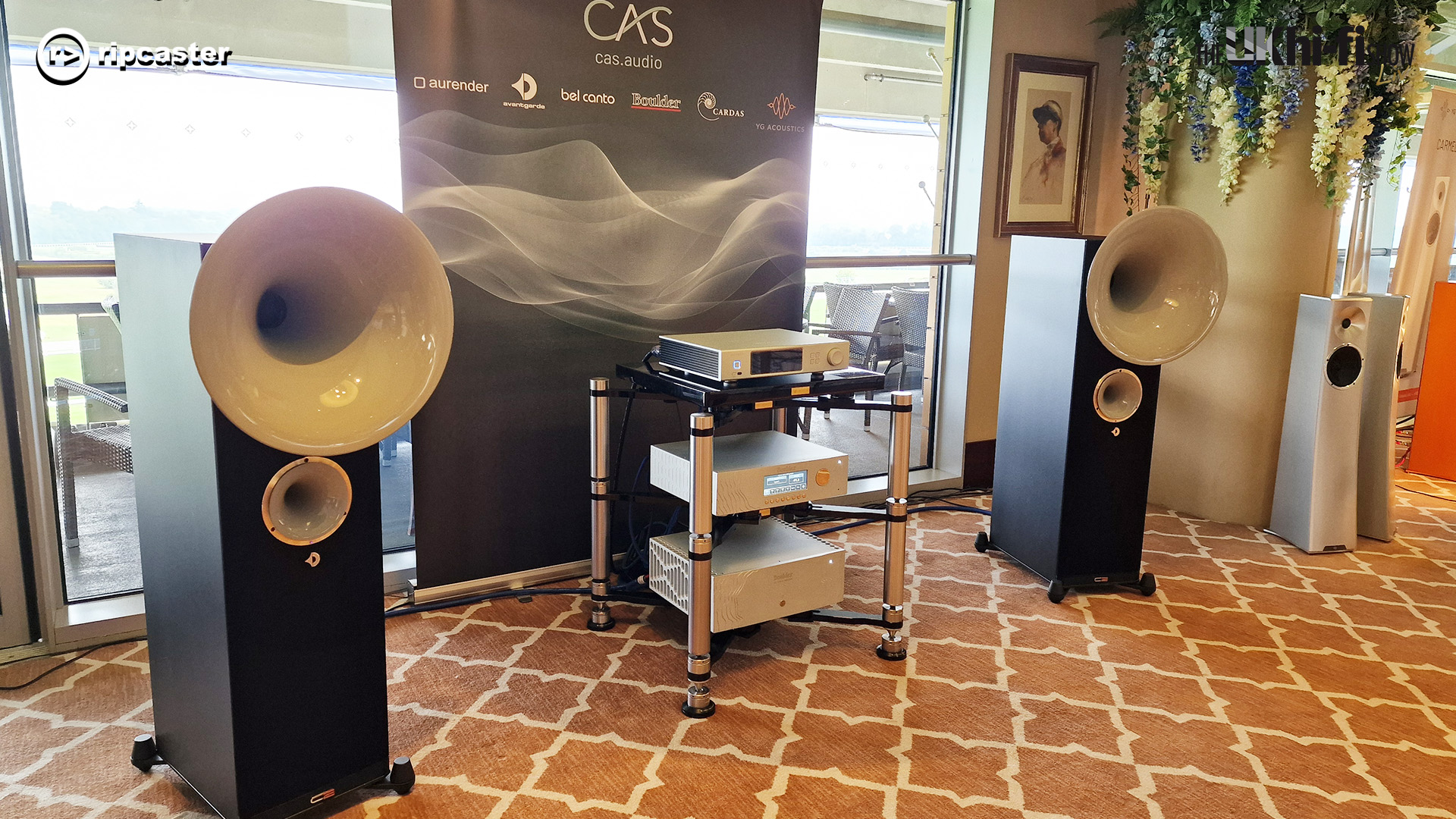 A pair of large floorstanding speakers with large funnel style bits at the top.  there's various bits of HiFi equipment between the speakers