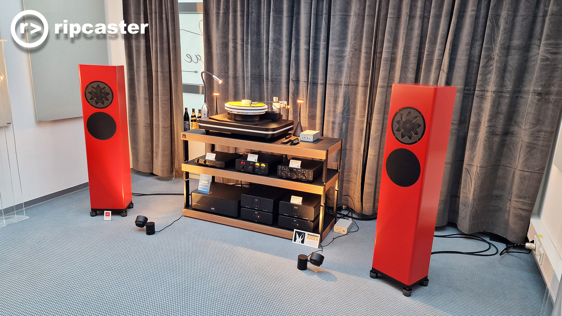 a pair of red floorstanding speakers with other hifi equipment between them