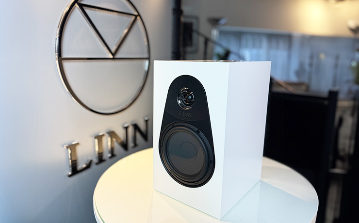 The Linn 119 speaker in white beside the ripcaster Linn sign. The speaker is on a white circular table