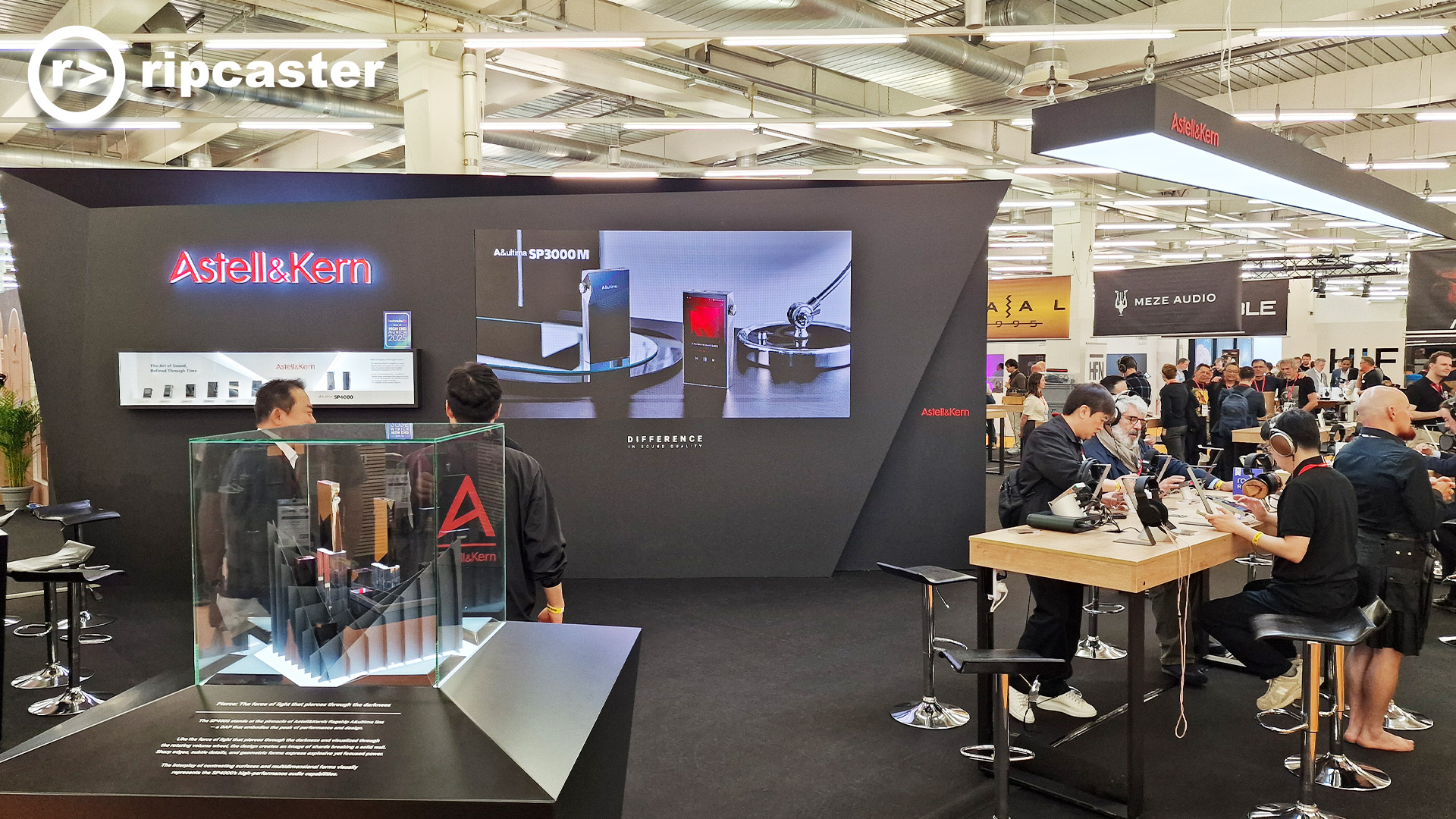 Astell & Kern at HiFi Munich.  This is their stand at the show.  There are a lot of people sitting on high stalls listening to music through headphones