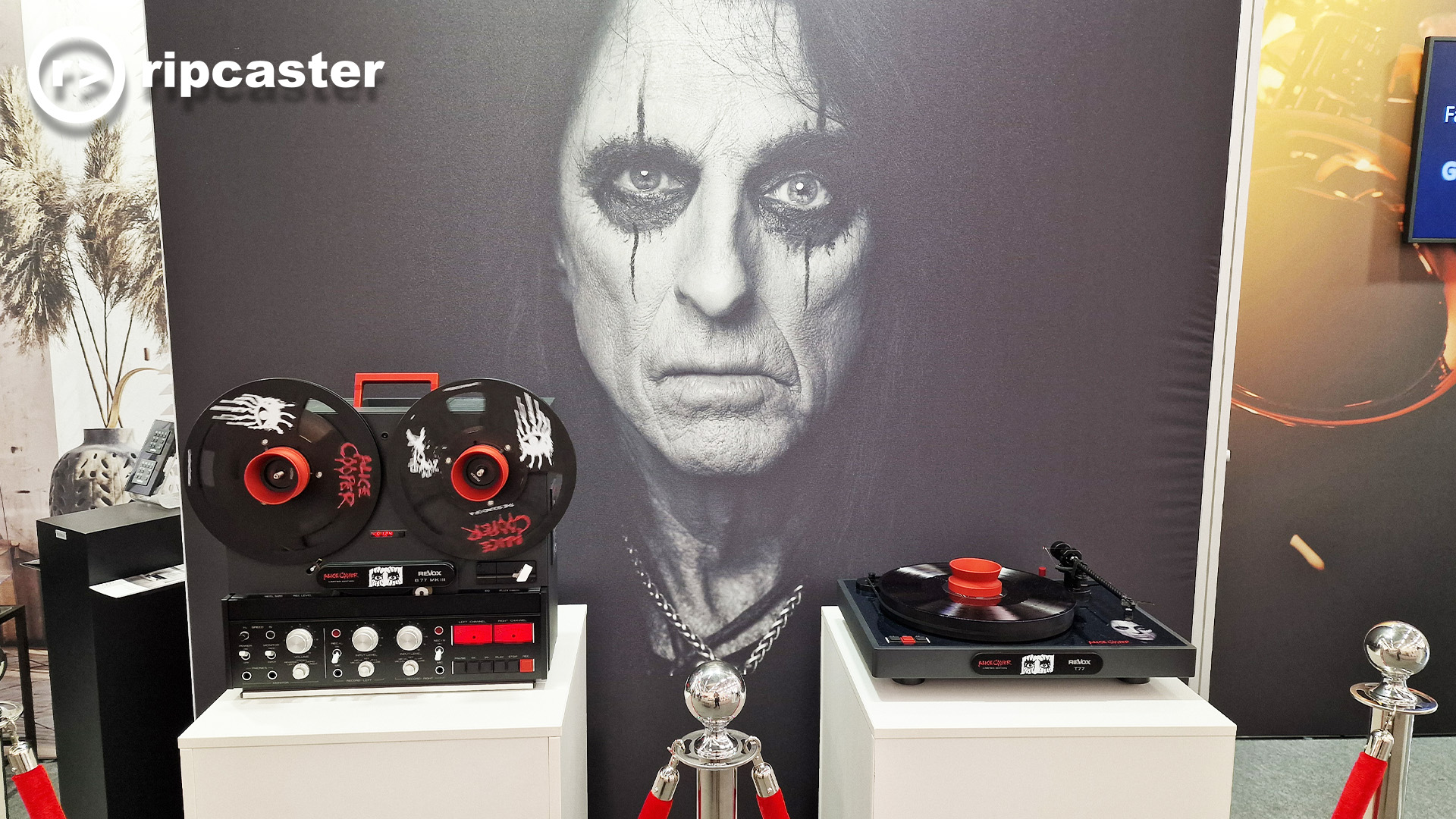 An Alice Cooper themed reel to reel and turntable with a large backdrop of Alice Cooper.