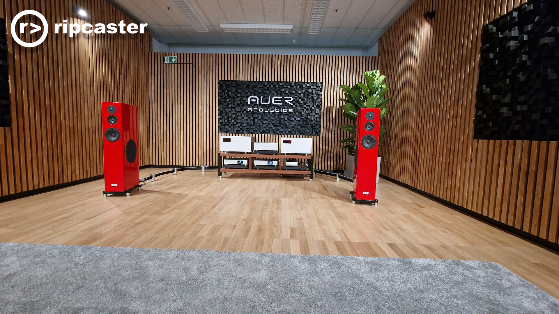 Red floorstanding speakers either side of HiFi equipment in a listening room at the HiFi Munich show.