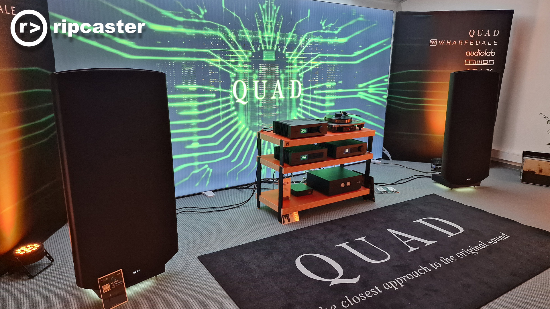 The Quad room at the Munich HiFi show with large floorstanding speakers and hifi equipment in between those speakers