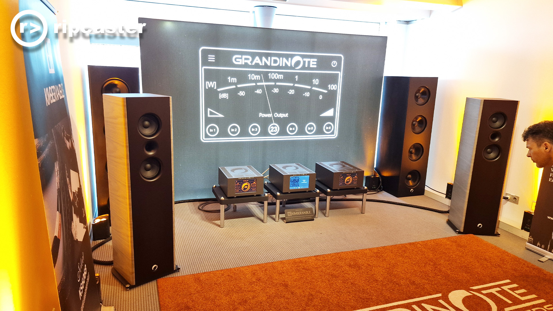 Floorstanding speakers in a HiFi room and a man's head poking into the frame of the photo from the right