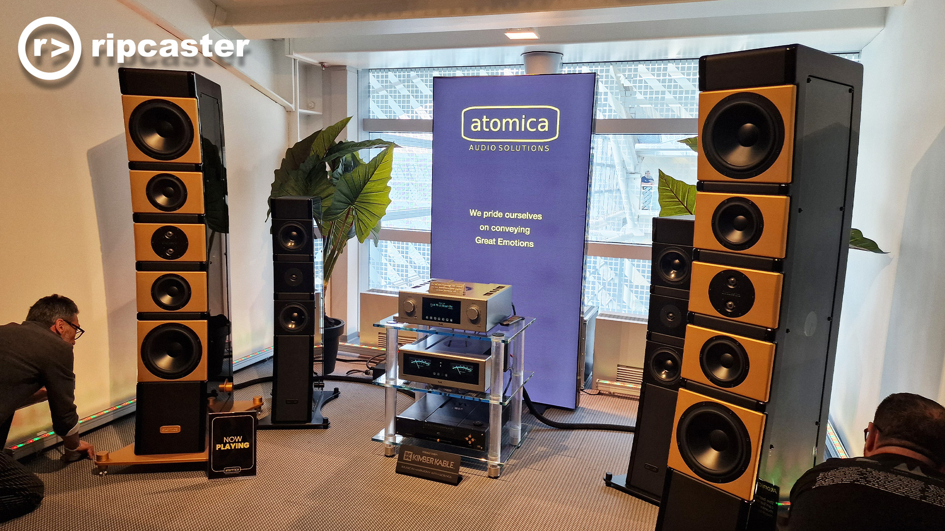 Very large floorstanding speakers with HiFi kit in the middle of them.  There's a man crouching down on the left of the image