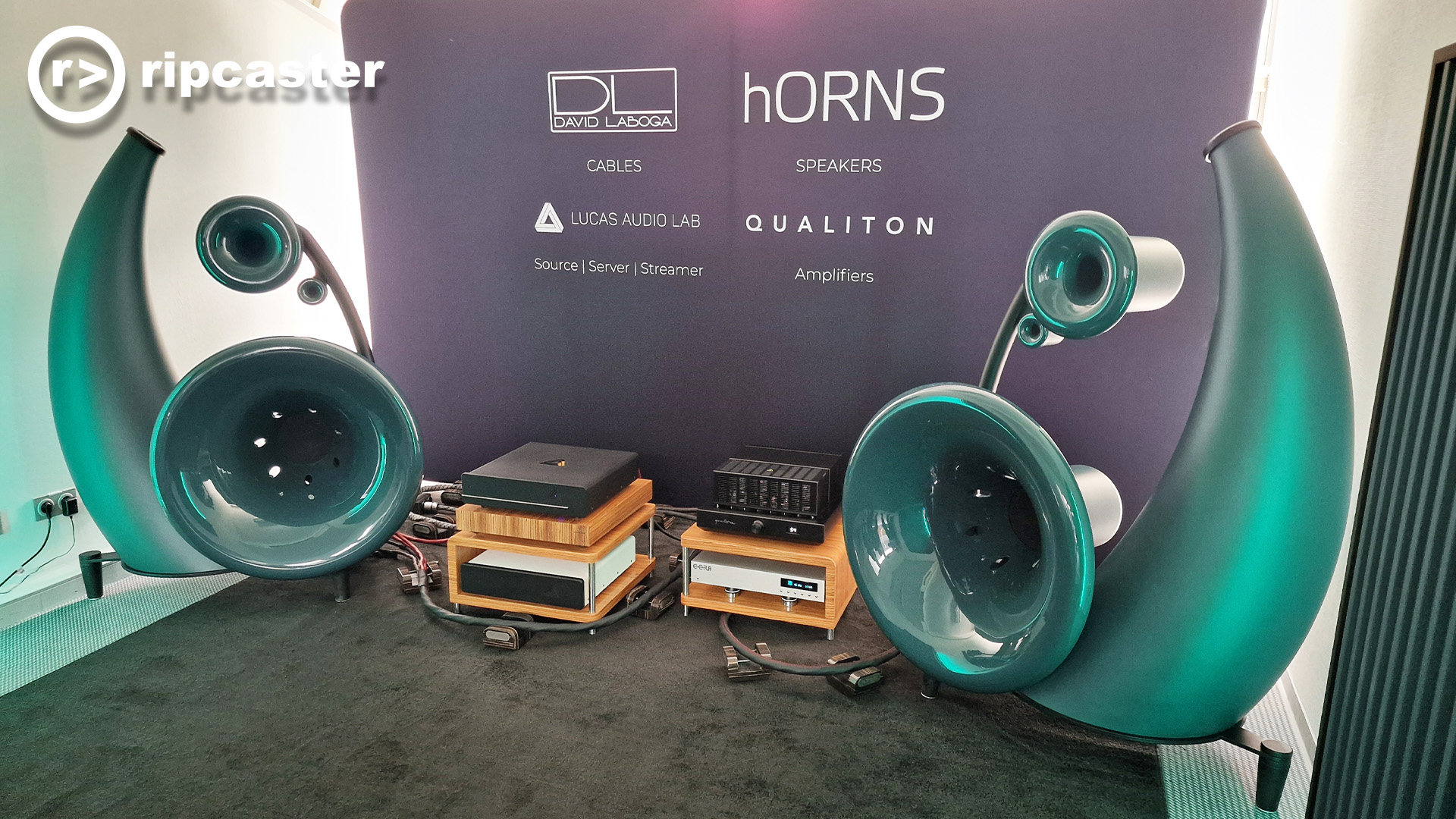 Green horn style speakers with Audio equipment between them in a listening room.
