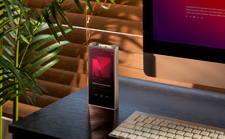 A PD20 standing up on a desk beside a typing keyboard with a monitor behind it