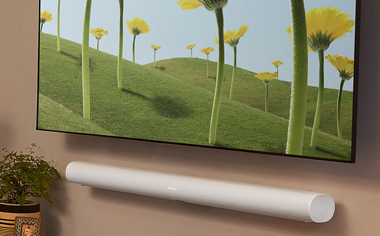 The SONOS Arc in white mounted onto a wall underneath a tv