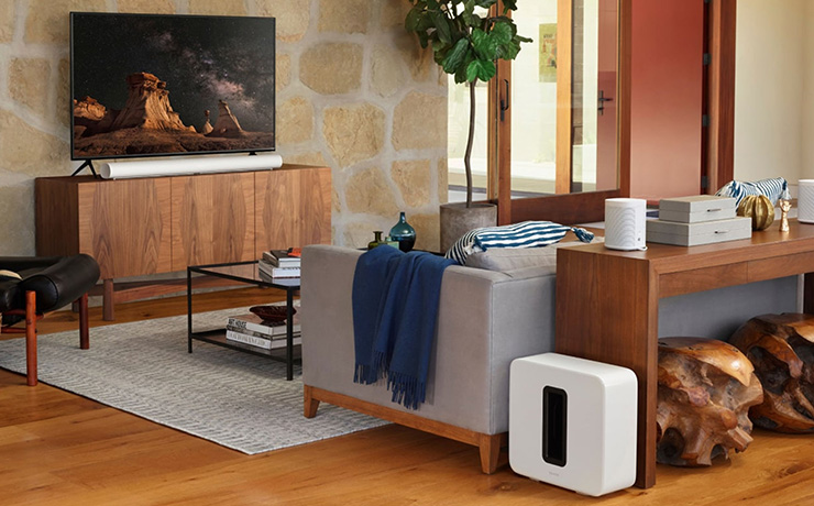 The SONOS Arc in a living space along with other SONOS products. the Arc is in front of a tv