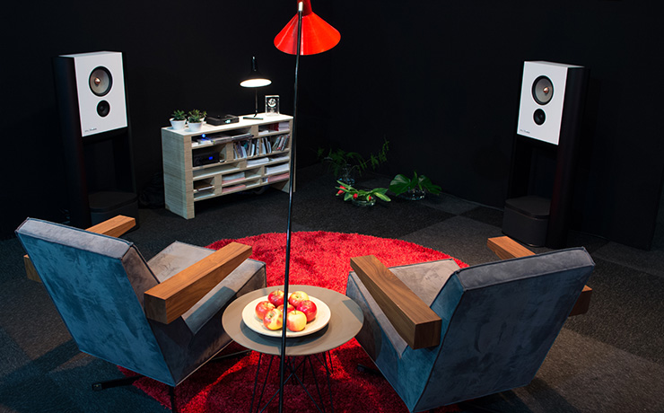 A pair of Grimm LS1be speakers in a room with a couple of chairs facing them and a low shelf unit.