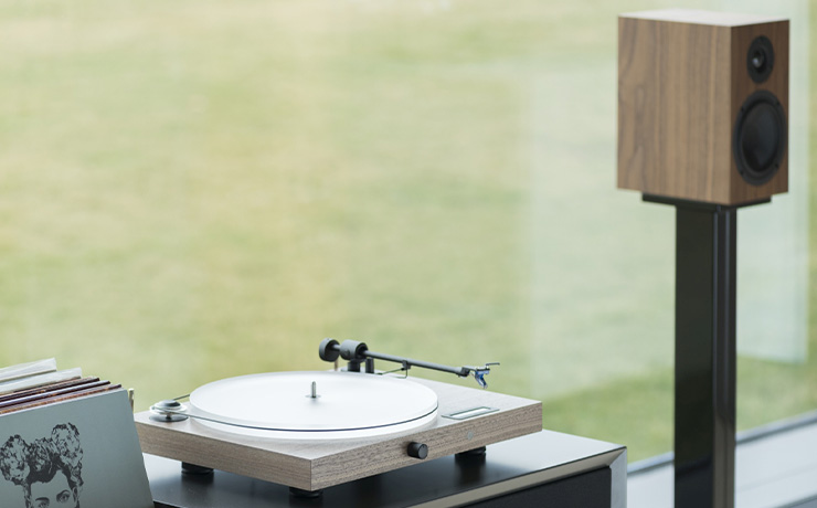 Project Juke Box S2 turntable on a low cabinet with records beside it and a speaker the other side