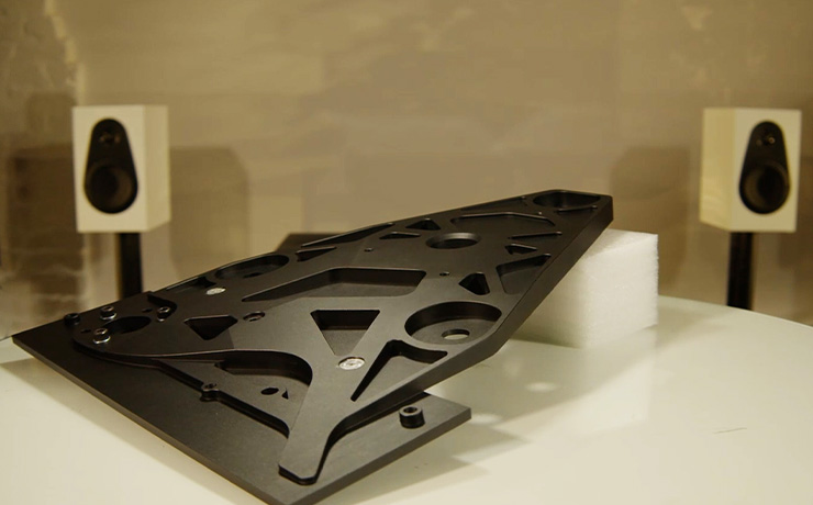 The underside of the Linn Keel SE with a pair of white Linn 119 speakers in the background