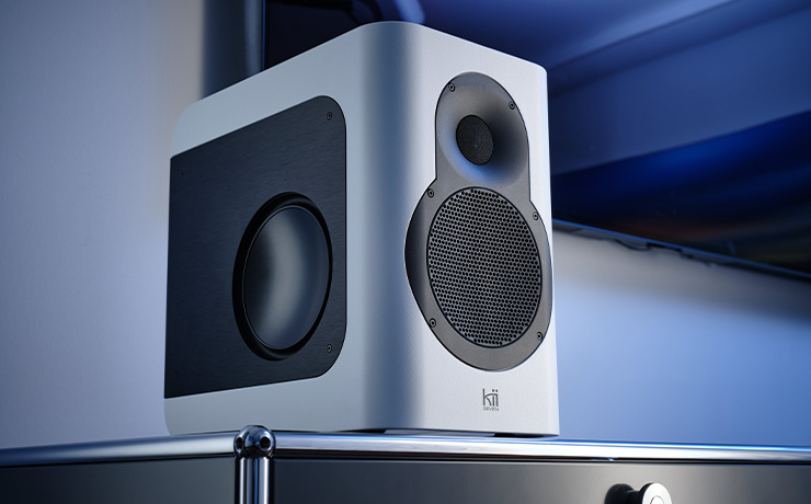 Kii Seven speaker in light grey standing on a modern unit