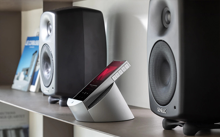 The Astell & Kern PD10 sitting on its cradle on a shelf between two bookshelf speakers