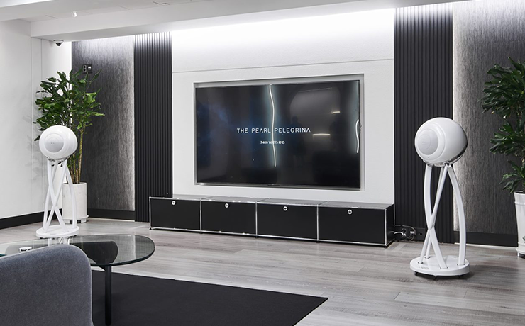 A pair of Cabasse Pearl Pelegrina speakers in white either side of a large tv screen.