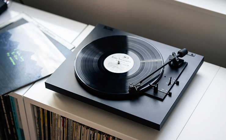 Project A1.2 turntable in black on top of a unit full of vinyl
