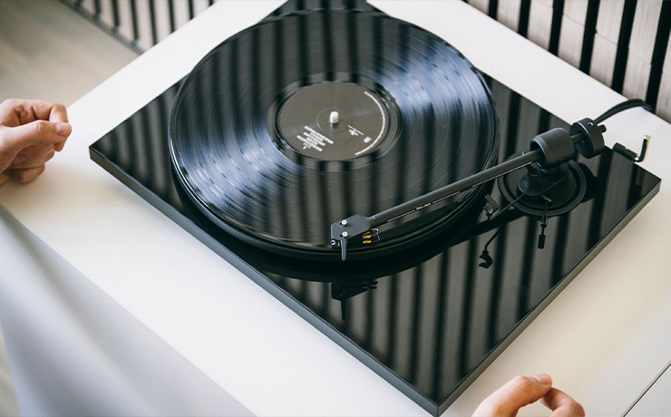 Project E1.2 turntable in black playing a record with hands in view
