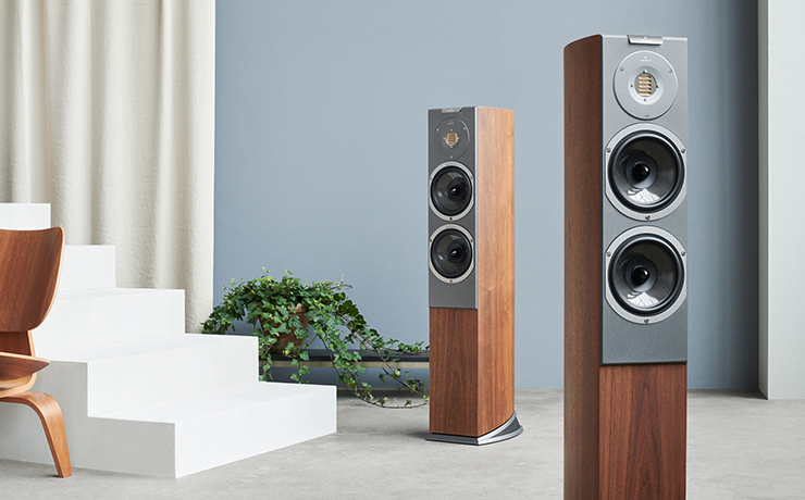 A pair of Audiovector R3 Arreté Loudspeakers in a room with some stairs and a chair to the side