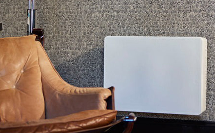 REL Planar PL-2 Subwoofer in white on a wall with a chair close to it