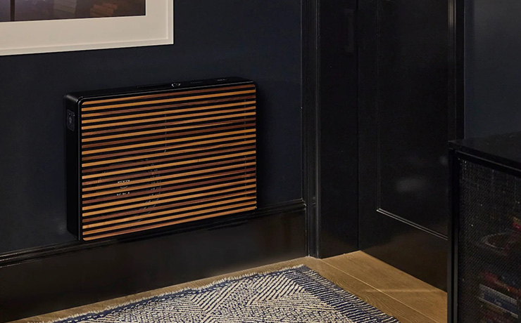 REL Planar PL-2 Subwoofer in black with a wooden grille on the wall in the corner of a room