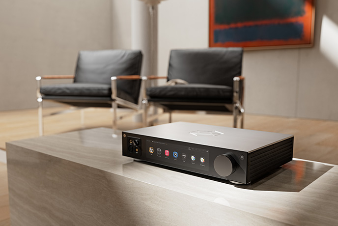 The HiFi Rose RS451 in silver on a low unit with two black chairs in the background