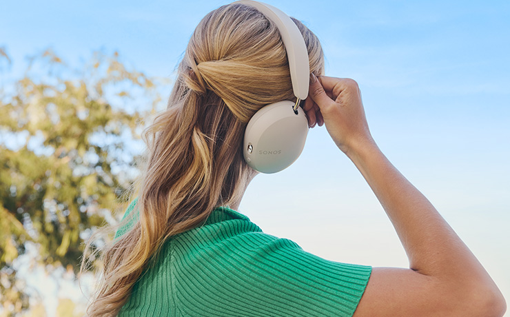 Sonos Ace heaphones in white being worn by a blonde woman on a sunny day