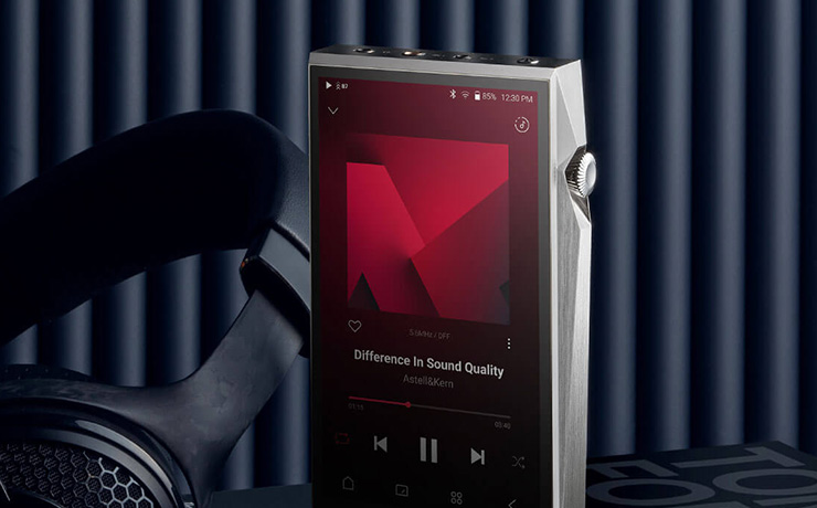 The A&K in silver standing up beside a pair of black headphones