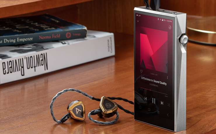 A&K SP3000T in silver standing on a table with some earphones plugged in.  There are books in the background.