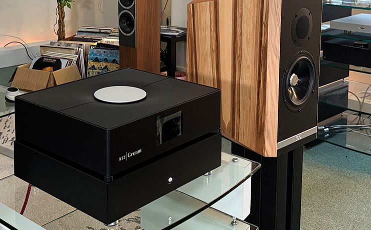 Ultrafide SP500 Stereo Power Amplifier on the top shelf of a HiFi rack with a Grimm MU2 stacked on top of it. There's a Kudos 505 speaker on a stand beside it