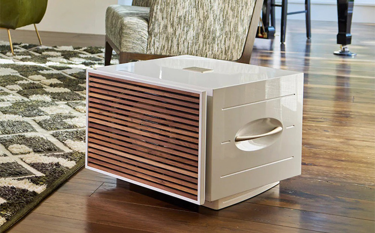 REL S/850 in white with the wooden grille on a wodden floor in a living space