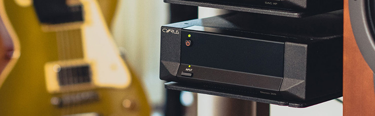 Cyrus Stereo 200 Power amplifier with a guitar on the left in the background