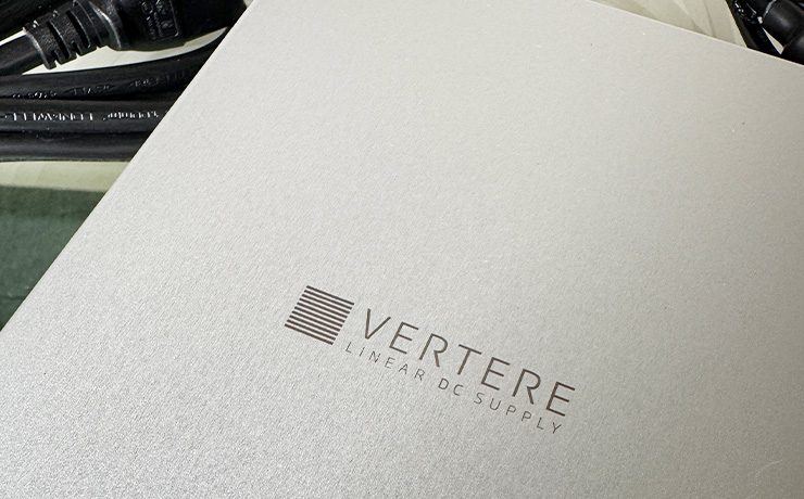 A photo of the top of the LunA - this is the ripcaster one which is silver and has the Vertere logo in shot with the words "Vertere" and, underneath "Linear DC Supply".  The power lead is partly visible top left