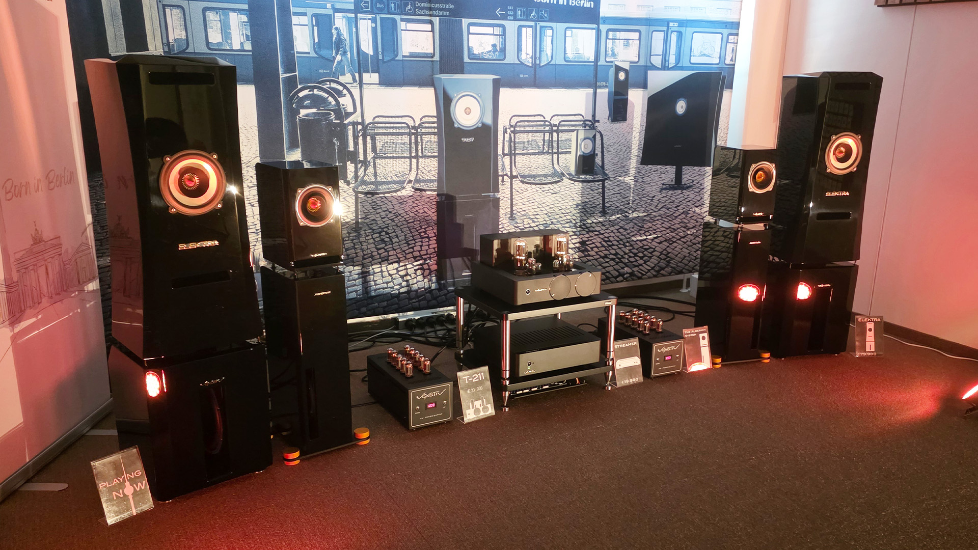 A room at the Vienna HiFi Show with large, black floorstanding speakers with HiFi units between