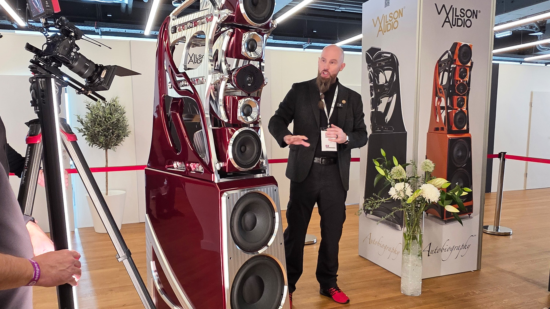 A large floorstanding speaker in red with a man standing beside it