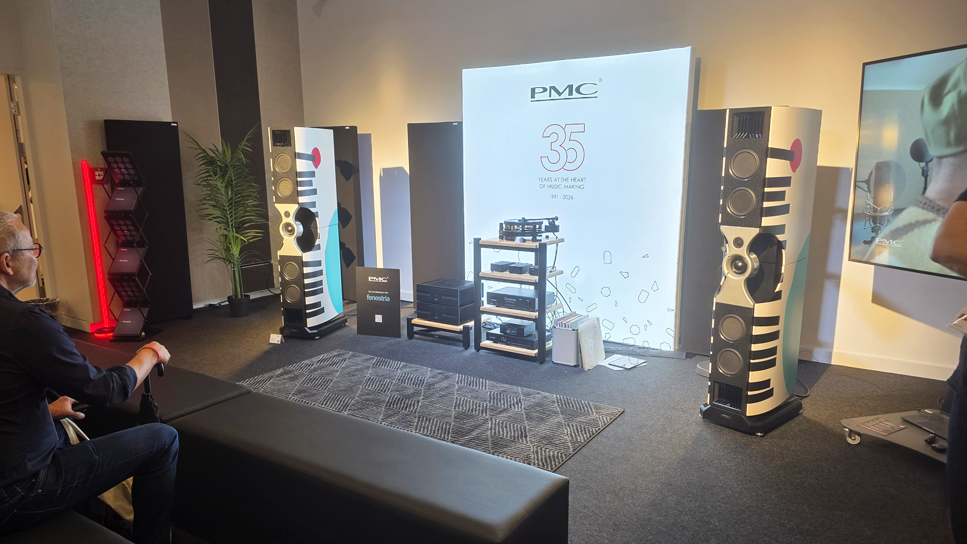The PMC room at the Vienna HiFi show.  Two white floorstanding speakers at the front