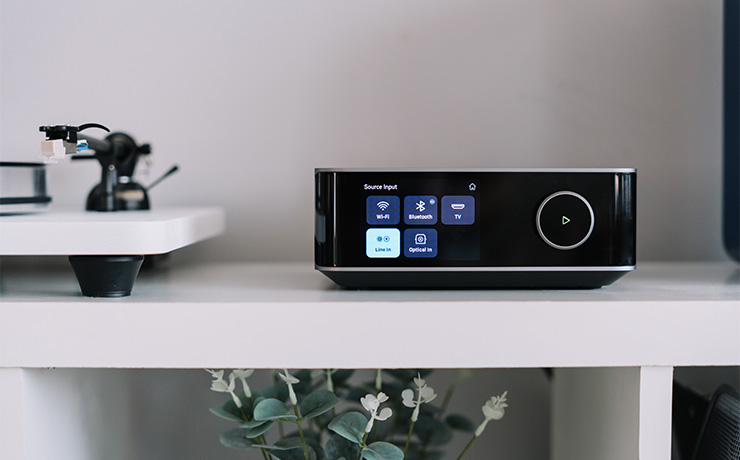 WiiM Amp Ultra on a white cube unit beside a turntable