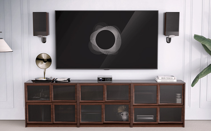 WiiM Amp Ultra on a low wooden unit.  There's a tv and speakers on the wall.