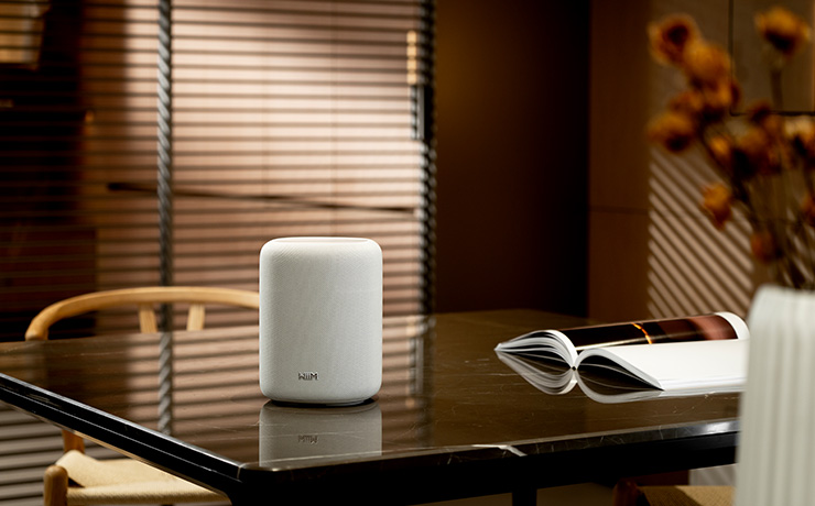 A white WiiM speaker on a table in a living space