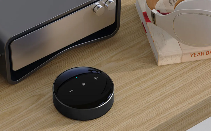 WiiM Mini on a table with a book by the side of it