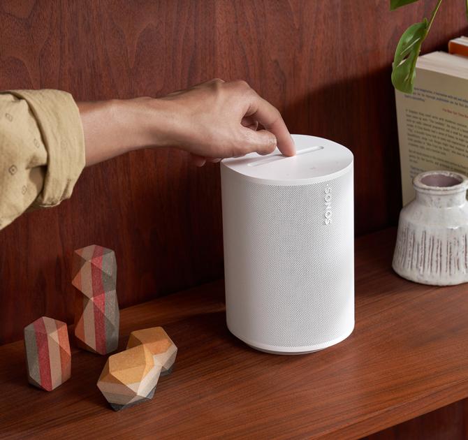 SONOS Era 100 Loudspeaker in white with a hand on the controls